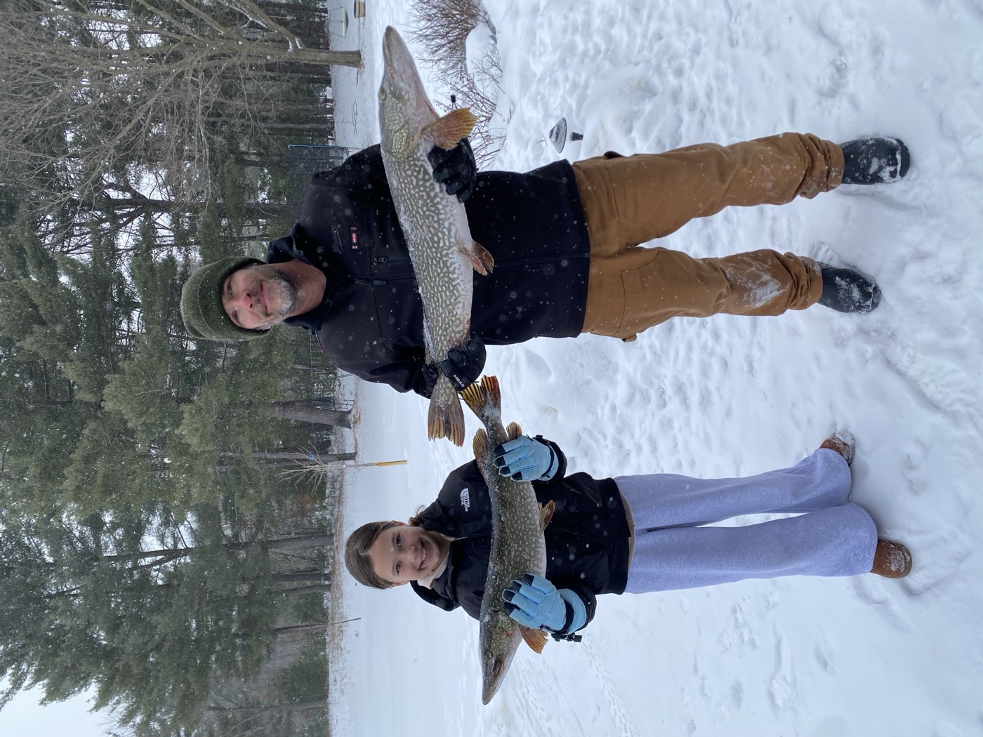 Casey and his daughter holding two northern pike on a snowy Wisconsin day